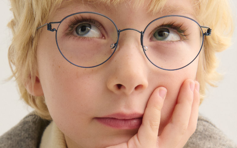 Blonder Junge mit blauer LINDBERG-Brille rollt mit den Augen